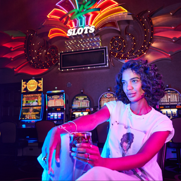 Curly haired young woman sitting in front of slot machine in Rio Hotel & Casino's High-Limit Slot Room
